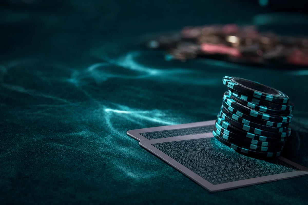 Stack of black and teal striped chips resting on two face-down cards on dark teal felt (AI-generated image)
